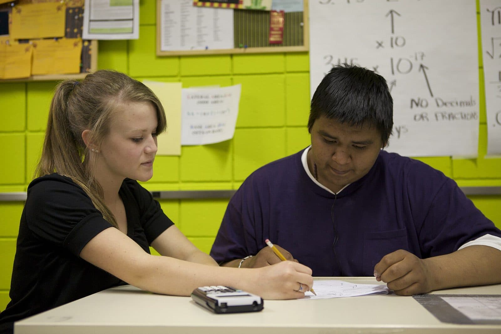 A tutor and a student working through math problems with a calculator